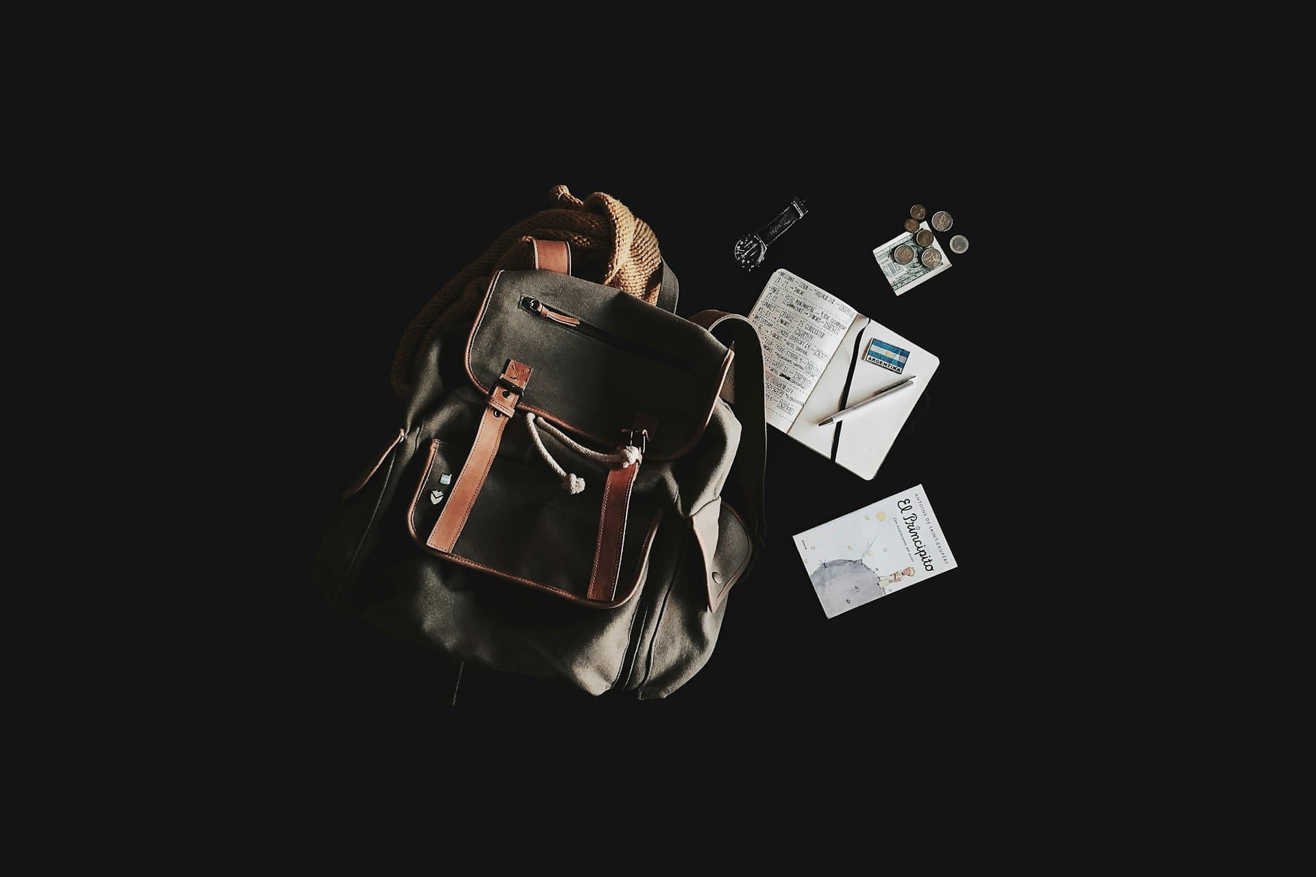Leather travel bag and everyday carry, laid out in warm, moody light